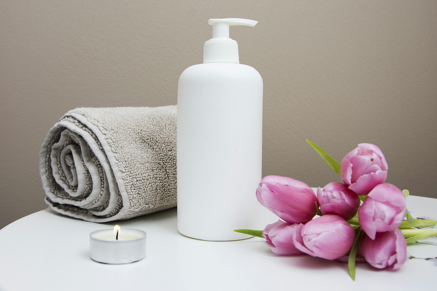 Warm stone spa setting with folded towels and a botanical branch